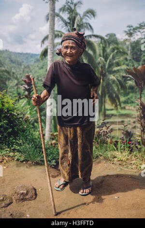 A piena lunghezza Ritratto di sorridere vecchia donna in piedi con un bastone. Femmina Senior all'aperto in campagna. Foto Stock
