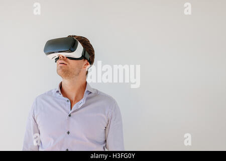 Colpo di giovane uomo in VR auricolare guardando lontano gli oggetti in realtà virtuale. Maschio caucasico con la realtà virtuale ancora gli occhiali di protezione Foto Stock
