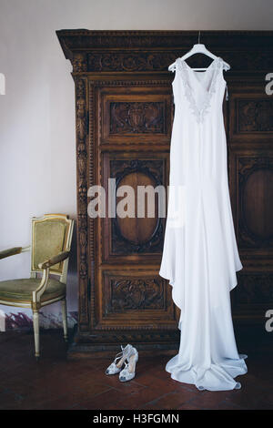 Abito da sposa appeso a un armadio con le scarpe Foto Stock