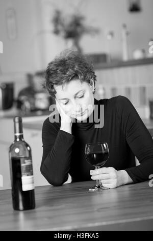 Fotografia in bianco e nero di una giovane donna nel dolore di bere vino rosso Foto Stock