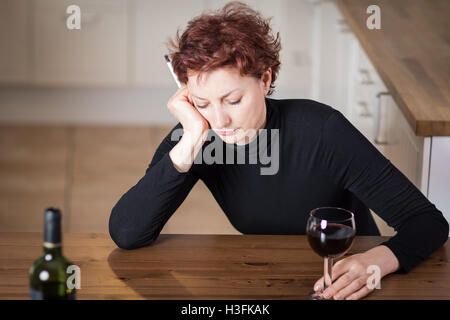 Giovane donna nel dolore di bere il vino rosso e fumare una sigaretta Foto Stock