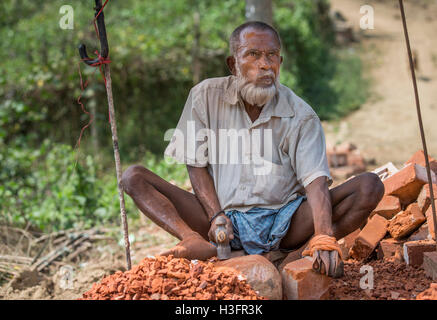 Chittagong, Bangladesh, Febbraio 25th, 2016: Vecchio distruggendo mattoni con un martello Foto Stock