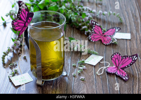 Decorazione di sfondo farfalle di carta in un bicchiere di tè alla menta. Tè alla menta, decorativi butterfly e foglie di menta fresca su Foto Stock