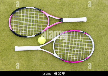 Sporty racchette da tennis con palla su sfondo verde Foto Stock