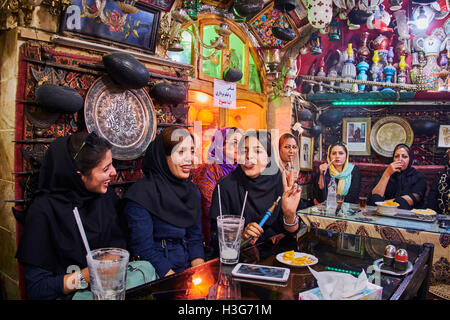 Iran, Isfahan, Azadegan teahouse, giovani donne di fumare un tubo di acqua Foto Stock