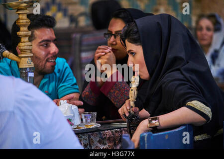 Iran, Kerman provincia, Kerman, Vakil hammam teahouse, donna iraniana di fumare un tubo di acqua Foto Stock