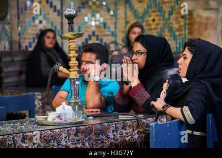 Iran, Kerman provincia, Kerman, Vakil hammam teahouse, donna iraniana di fumare un tubo di acqua Foto Stock