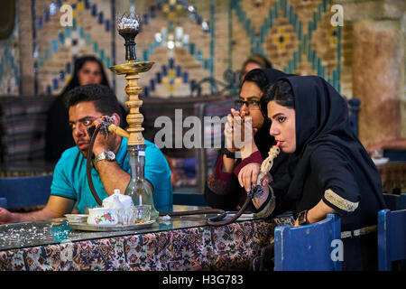 Iran, Kerman provincia, Kerman, Vakil hammam teahouse, donna iraniana di fumare un tubo di acqua Foto Stock