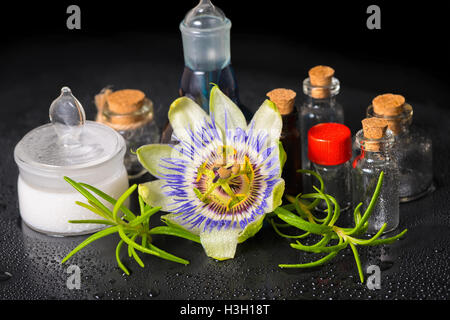 Bellissima spa impostazione di passiflora blu fiore, sale cosmetiche mortaio e fragranza di bottiglie vuote sulle pietre zen con rugiada, chiudi Foto Stock