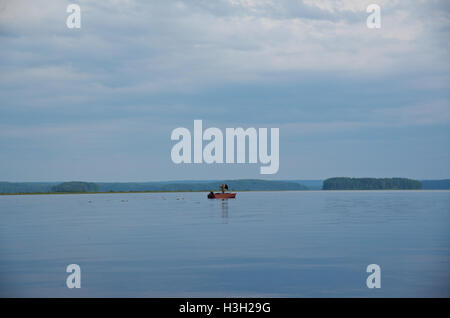 Il lago di Kenozero . Barca con pescatore sull'acqua. Regione di Arkhangelsk, Russia Foto Stock