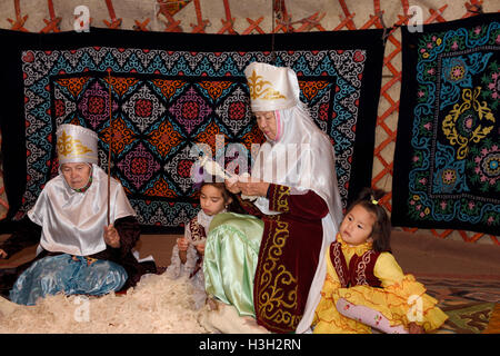 Nonne e bambini in yurta di battitura e la filatura della lana Unni village Kazakistan Foto Stock