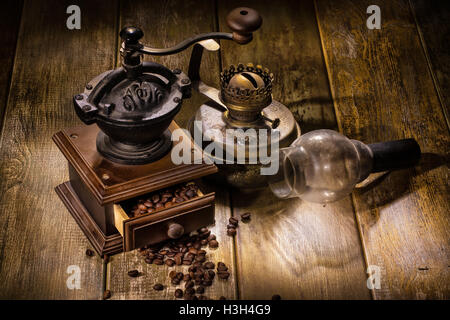 Coffee Mill e il vecchio olio lampada su un tavolo di legno Foto Stock