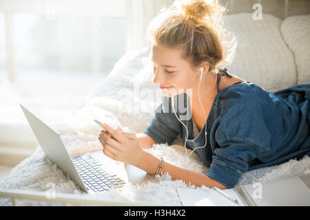 Ritratto di una donna attraente giacente sul letto con il computer portatile Foto Stock