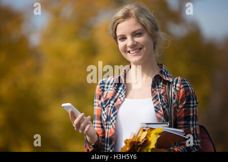 Ritratto di studente outsides, tenendo il telefono cellulare in una mano Foto Stock