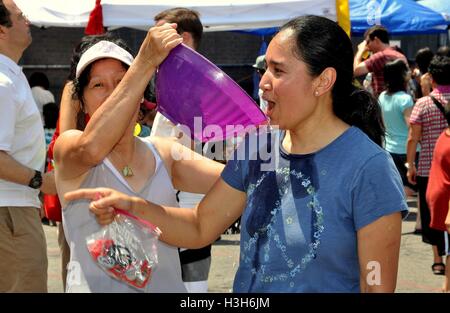 New York City - Luglio 18, 2010: Donna scarica una ciotola di acqua sul suo amico al XVI Thingyan annuale birmano Festival di acqua Foto Stock