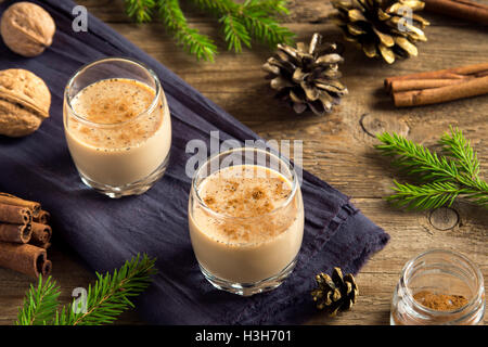 Zabaione con cannella in bicchieri su legno rustico sfondo con decorazioni di Natale - fatti in casa di festa di Natale bere Foto Stock