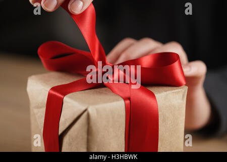 Teen femmina lato andando a sciogliere arco sulla confezione regalo Foto Stock