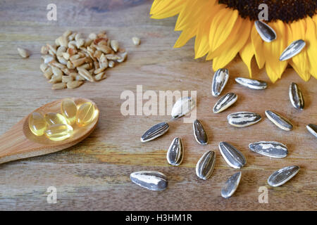 Semi di girasole e di supplementi di vitamina E su sfondo in legno e decorate con un girasole Foto Stock