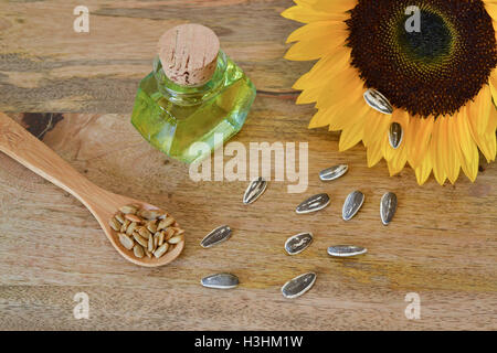 Semi di girasole e olio su tavola di legno, decorato con un luminoso giallo girasole Foto Stock