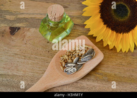 Semi di girasole e olio su tavola di legno, decorato con un luminoso giallo girasole Foto Stock