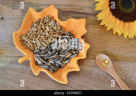 Semi di girasole e di supplementi di vitamina E sulla tavola di legno, decorato con un luminoso giallo girasole Foto Stock