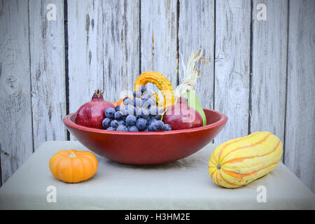 Primo piano su frutta e verdura raccolti nella fine dell'estate, nel cesto di rosso, sulla tovaglia di marrone chiaro e decorate con mais indiano Foto Stock