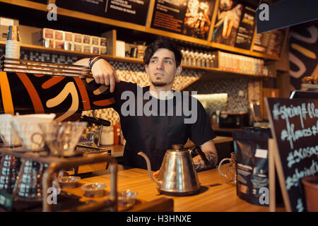 Barista a lavorare in un negozio di caffè Foto Stock