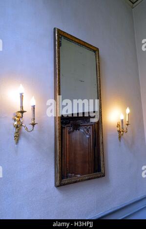 Specchio antico su un muro bianco con due candelabri. Foto Stock