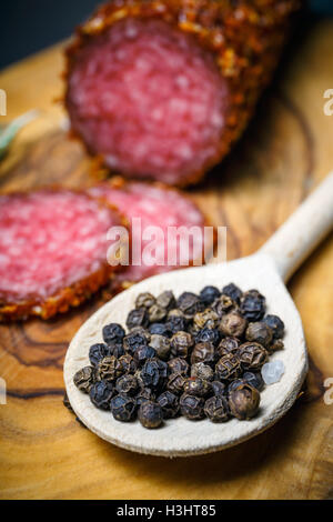 Salame essiccato in crosta nella massa di peperone rosso su sfondo scuro Foto Stock