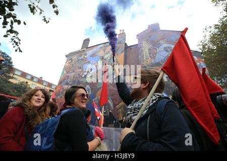 Un dimostrante rilascia una svasatura di fumo nella parte anteriore di un murale sul cavo Street nell'East End di Londra, che commemora la Battaglia di Cable Street. Foto Stock