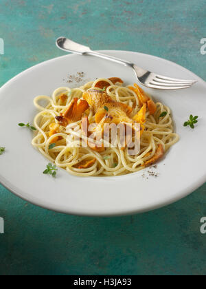 Wiild chanterelle organico o girolle funghi (Cantharellus cibarius) o saltate in burro e hebs con spaghetti Foto Stock