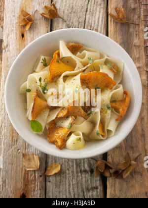 Wiild chanterelle organico o girolle funghi (Cantharellus cibarius) o saltate nel burro con pasta papedelle Foto Stock