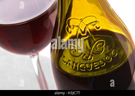 Bicchiere di vino rosso Languedoc e bottiglia goffrata sulla terrazza soleggiata Tabella Francia meridionale Foto Stock