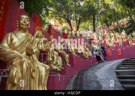 Giovane appoggiato accanto a decine di golden statue di Buddha lungo il percorso per il Monastero dei Diecimila Buddha (l'uomo grasso Tsz) in Hong Kong Foto Stock