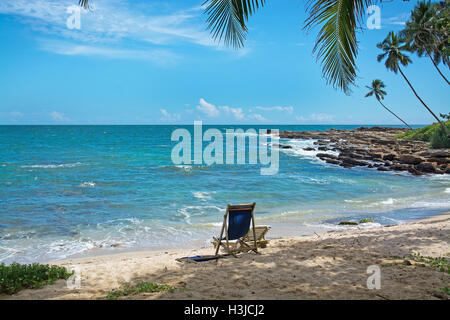 Semplice legno blu sedia a sdraio in spiaggia sabbiosa dall'Oceano Indiano su una spiaggia in Sri Lanka, in Asia. Foto Stock