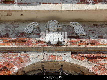 Cherubino decorativo sul muro di mattoni di un tempio abbandonato Foto Stock