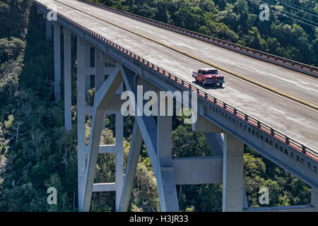 Rosso auto cubano attraversando il famoso Ponte di Bacunayagua, vicino a Matanzas, Mayabeque Provincia, Cuba Foto Stock