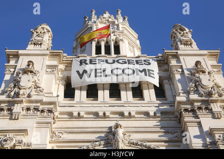 Un banner accogliendo i rifugiati pende dal Cibele Palace Madrid municipio della città sulla Plaza de Cibeles, Madrid, Spagna Foto Stock