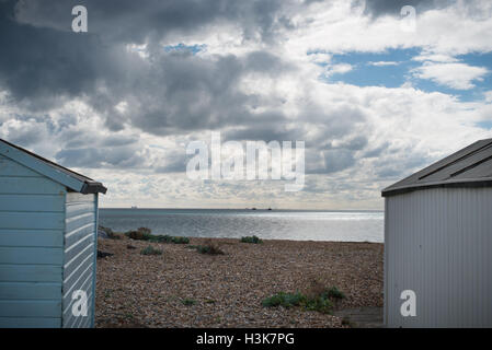 Un drammatico cielo pieno di nuvole sopra beach capanne sulla spiaggia a Lancing, West Sussex, in Inghilterra. Foto Stock