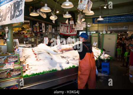 Fish monger gettando ghiaccio sul pesce in vendita presso il Pike Place Fish Market - Seattle, WA Foto Stock
