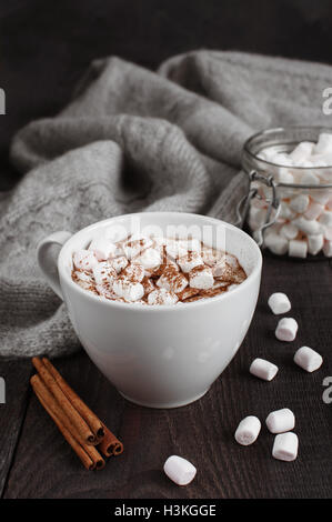 La tazza di bevanda con marshmallow sul buio tavolo in legno Foto Stock