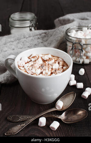 La tazza di bevanda con marshmallow sul buio tavolo in legno Foto Stock