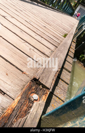 Ampio angolo di vista obliqua di una passerella di legno attraverso il Passirio Merano, Fiume travi danneggiate in primo piano. Foto Stock