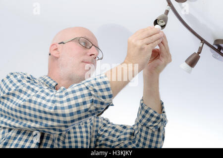 Un uomo maturo la sostituzione della lampadina della luce a casa Foto Stock