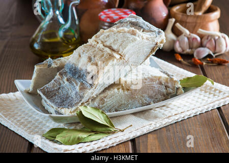 Stoccafisso tagliato con ingredienti e utensili sul tavolo della cucina per cucinare Foto Stock