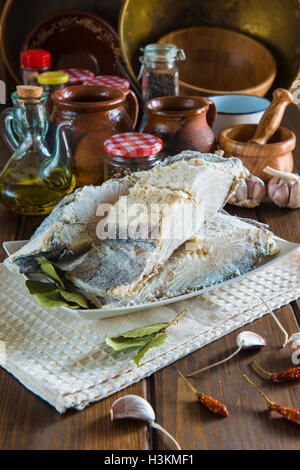 Stoccafisso tagliato con ingredienti e utensili sul tavolo della cucina per cucinare Foto Stock