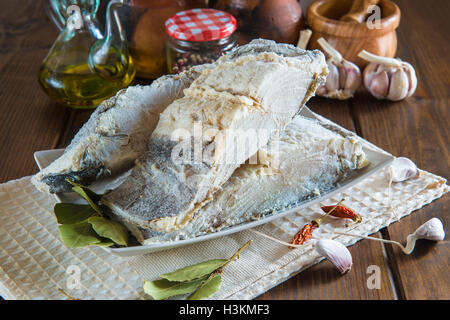 Stoccafisso tagliato con ingredienti e utensili sul tavolo della cucina per cucinare Foto Stock