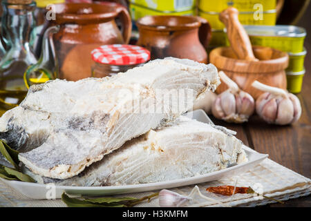 Stoccafisso tagliato con ingredienti e utensili sul tavolo della cucina per cucinare Foto Stock