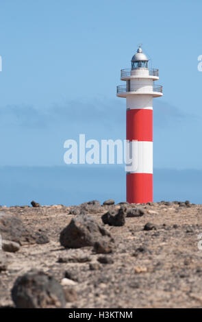 Fuerteventura: rocce e vegetazione con El Tostón Faro de Tostón o El Cotillo Faro) sullo sfondo Foto Stock