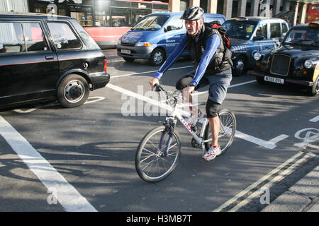 Ciclista attende al semaforo sulla sezione di priorità di percorso in bicicletta sul Bridge Street, Westminster. Mattina di sole in ottobre. © P Foto Stock